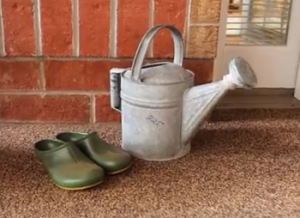 Watering can and gardening shoes on the porch